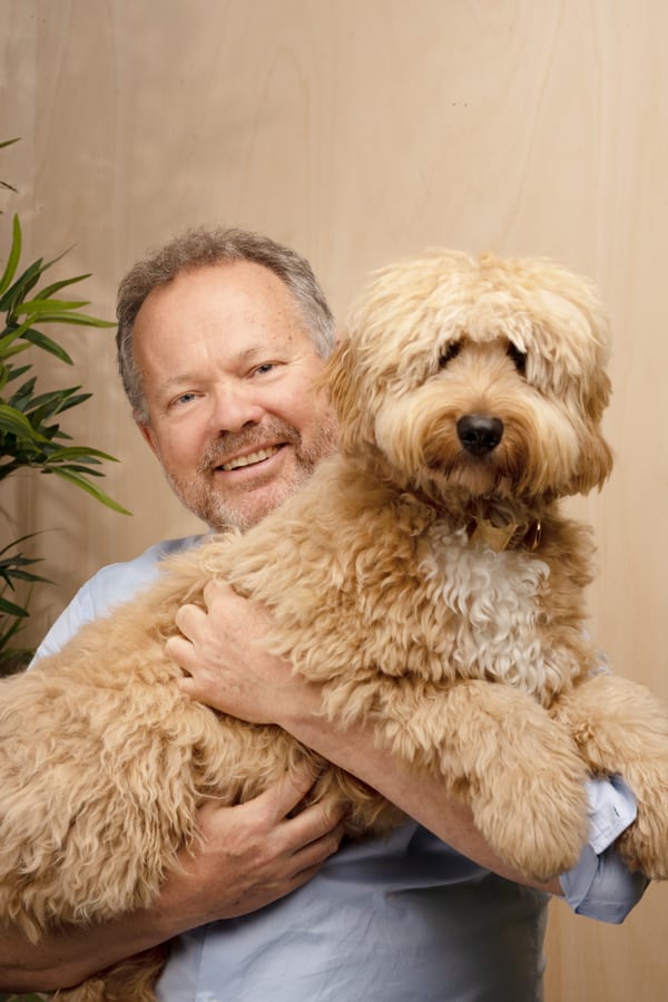 Dezelfde man met een lichtbruine labradoodle op de arm