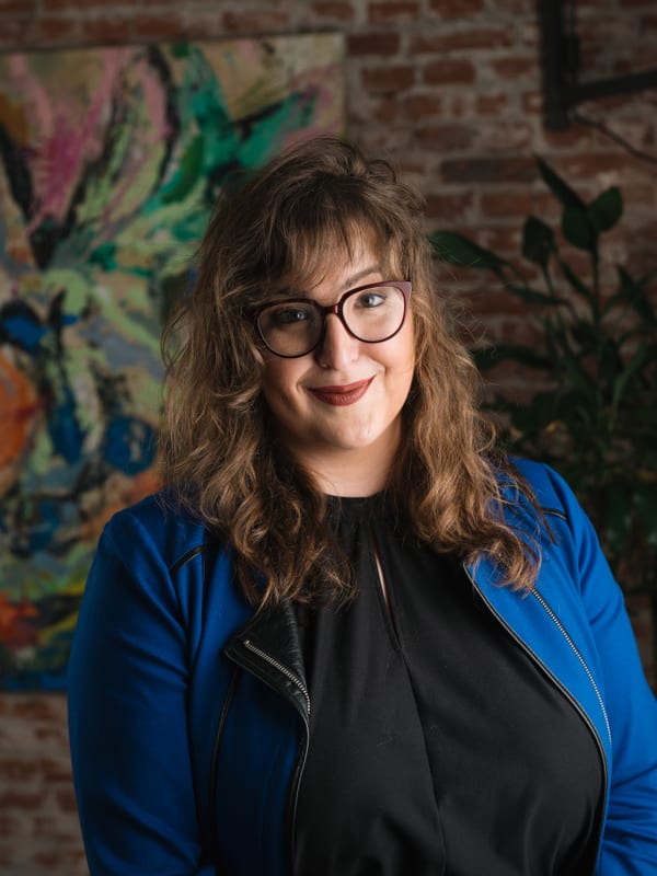 Vrouw met bril in een blauw jack over een zwarte top