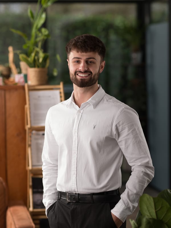Man met baard in een wit overhemd, handen in de zakken