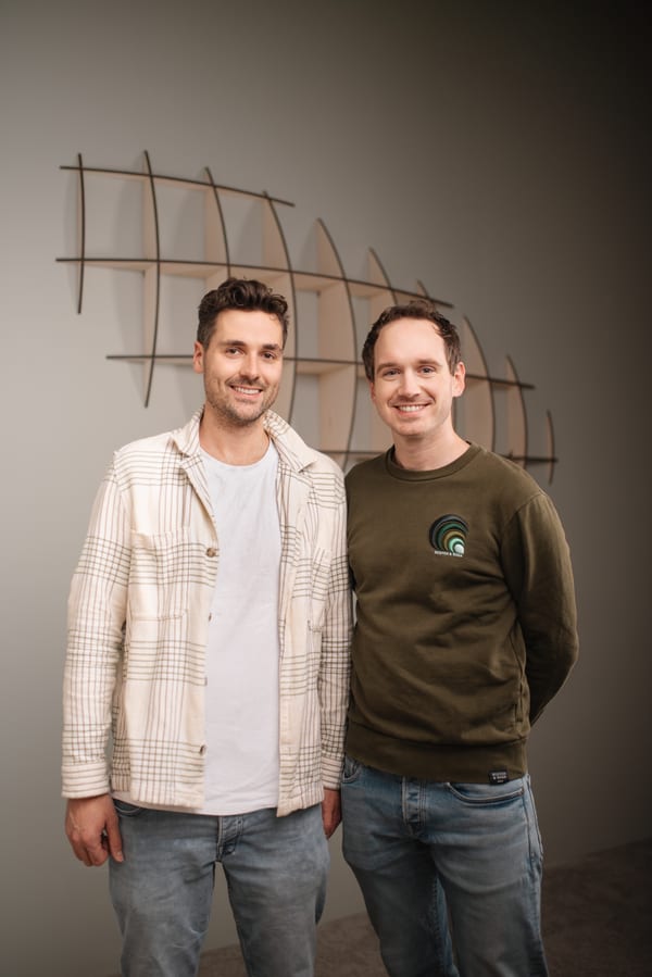 De twee makers naast elkaar, met het wandobject aan de wand achter hen